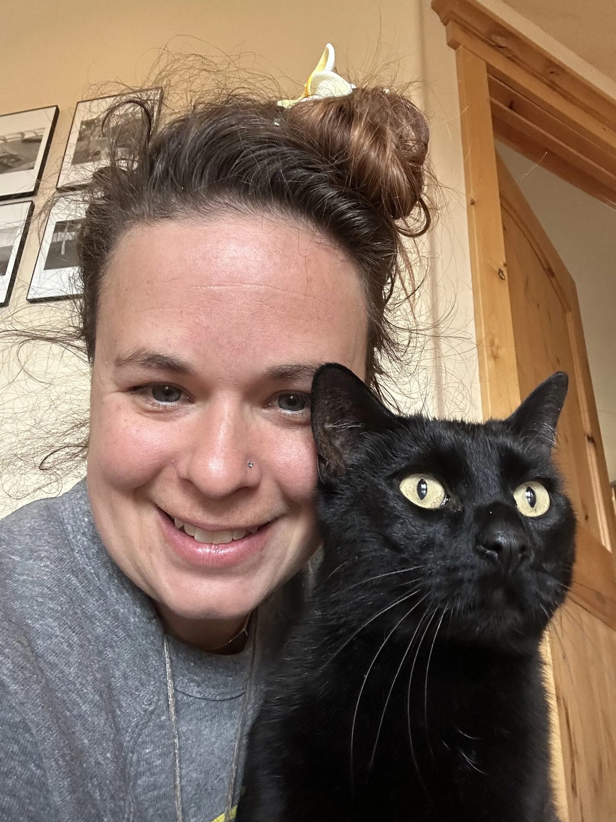 Lauren, owner of Purrrfect Care, smiling cheek to cheek with her black cat at home